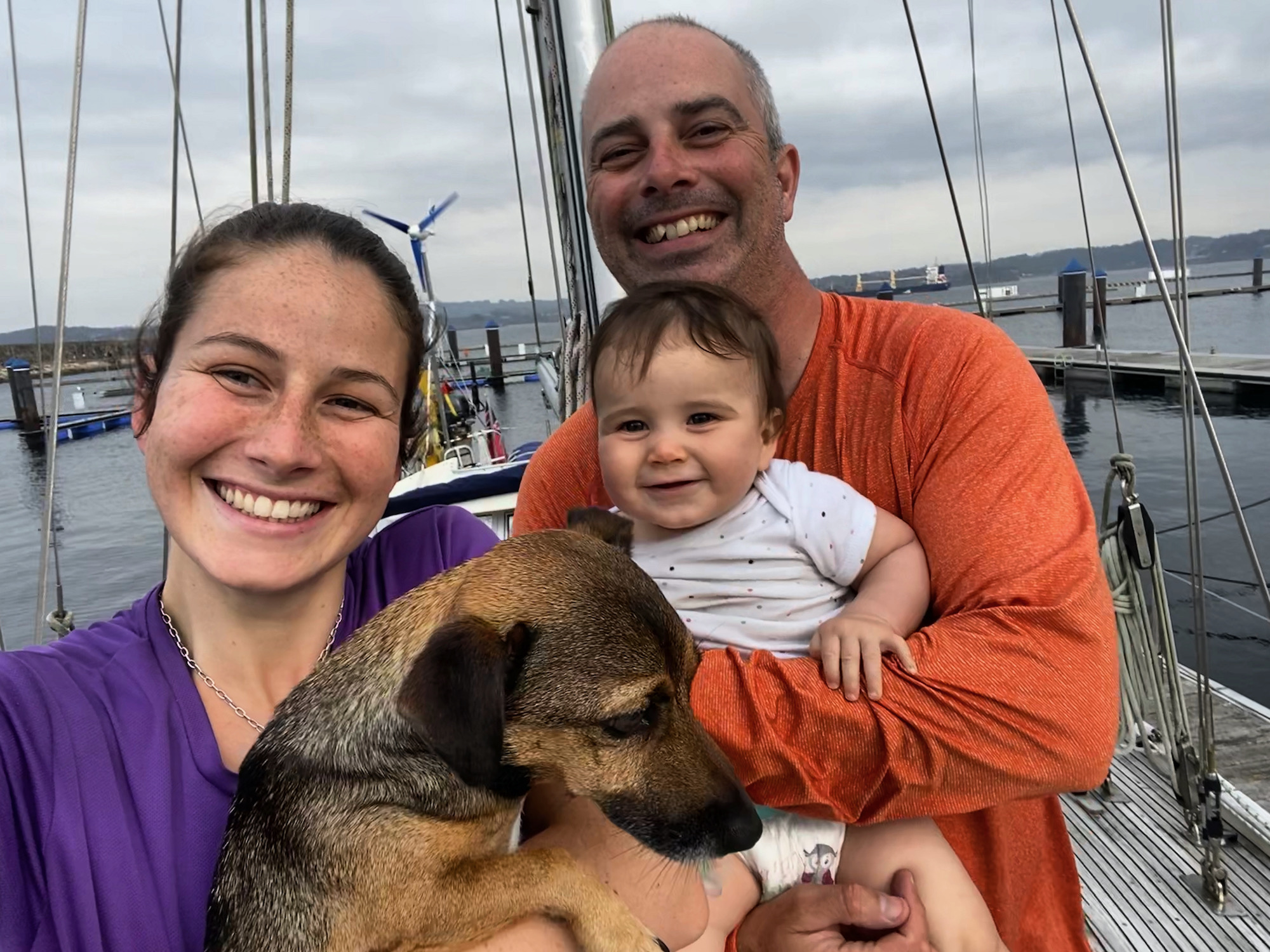family of three plus a dog on their sailboat excited after completing a crossing of the Bay of Biscay